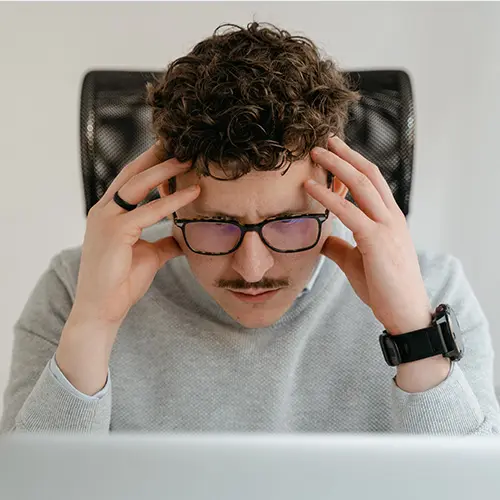 Homme se tenant la tête avec ses mains devant son ordinateur